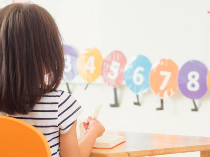 Una pequeña, de espaldas, en un aula escolar