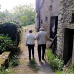Una pareja de personas mayores paseando por un pueblo